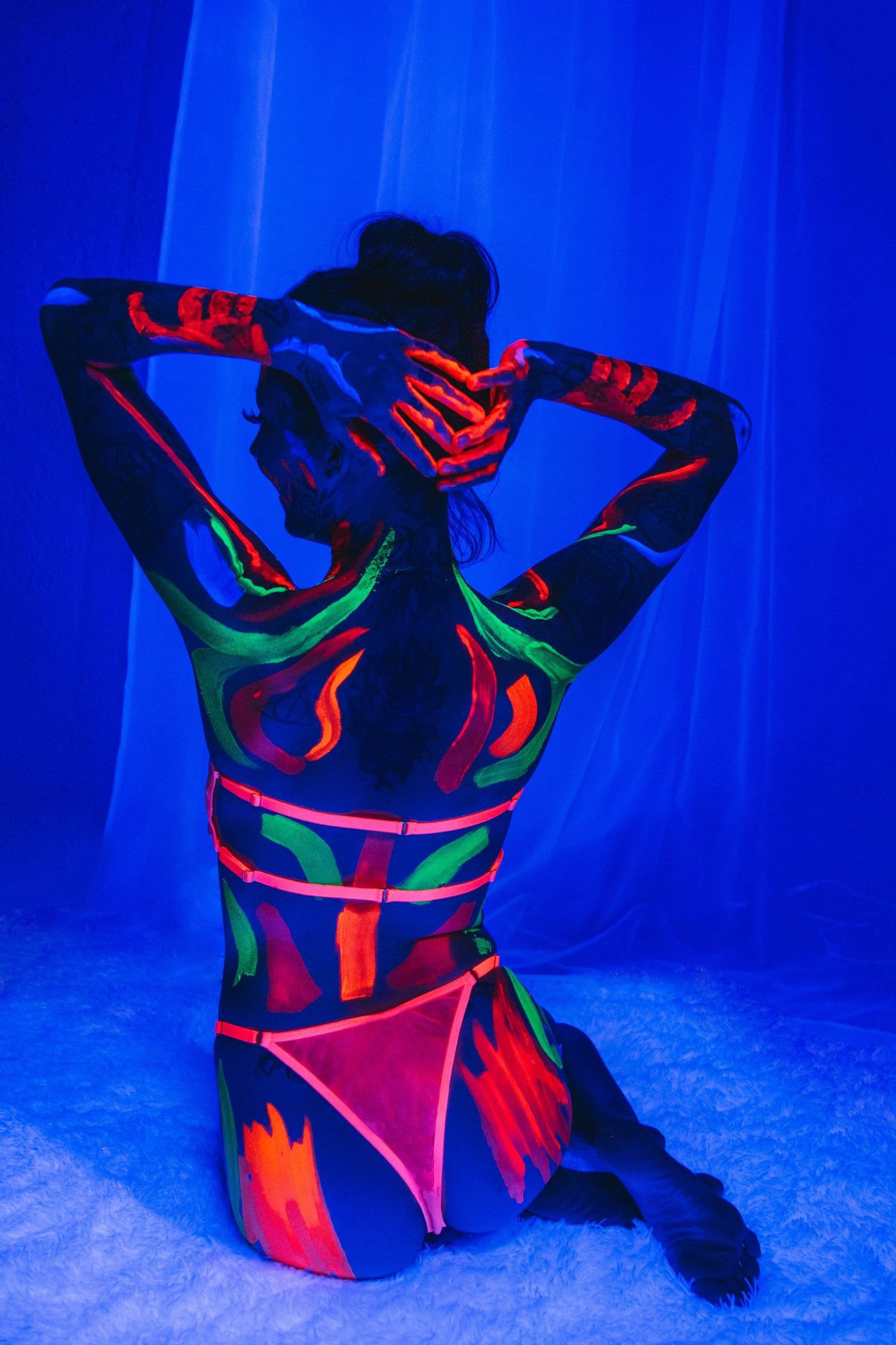Client posing confidently in dark room with glowing paint.
