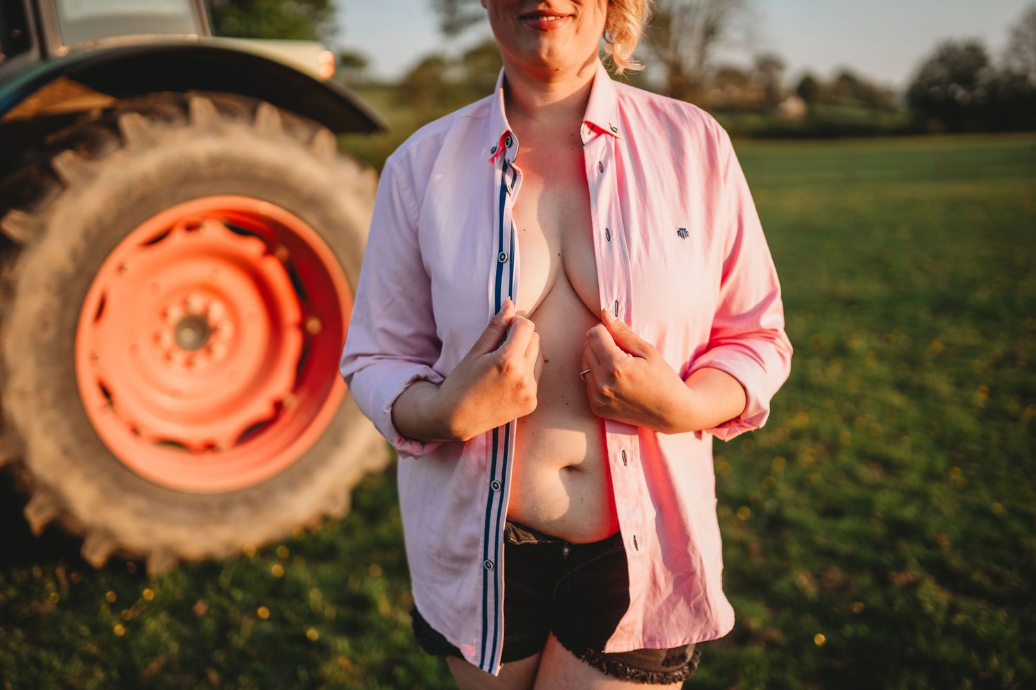 Artistic portrait session at golden hour with tractor wheel in background.