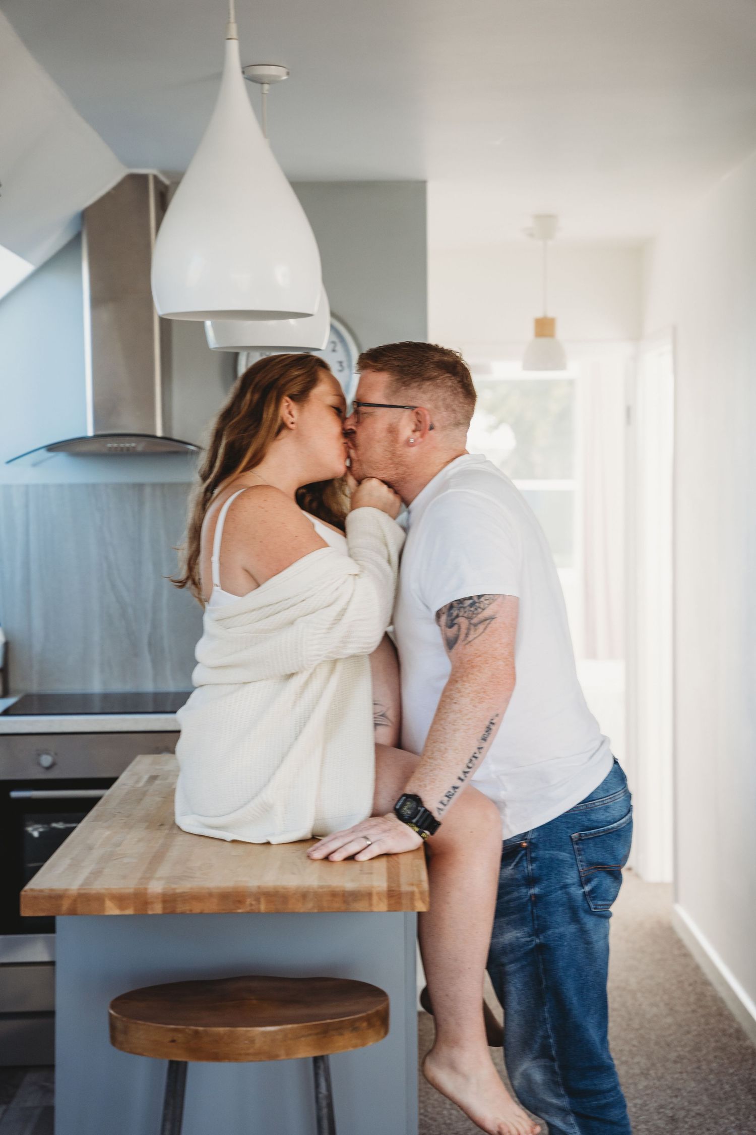 A couple shares an intimate moment on a wooden kitchen counter.