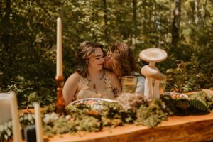 The newlyweds sit at a woodland table decorated with moss and candles; Lane kisses Kendall on the cheek affectionately.