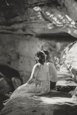 Black and white image of the couple sitting on a rocky overhang in Red River Gorge.