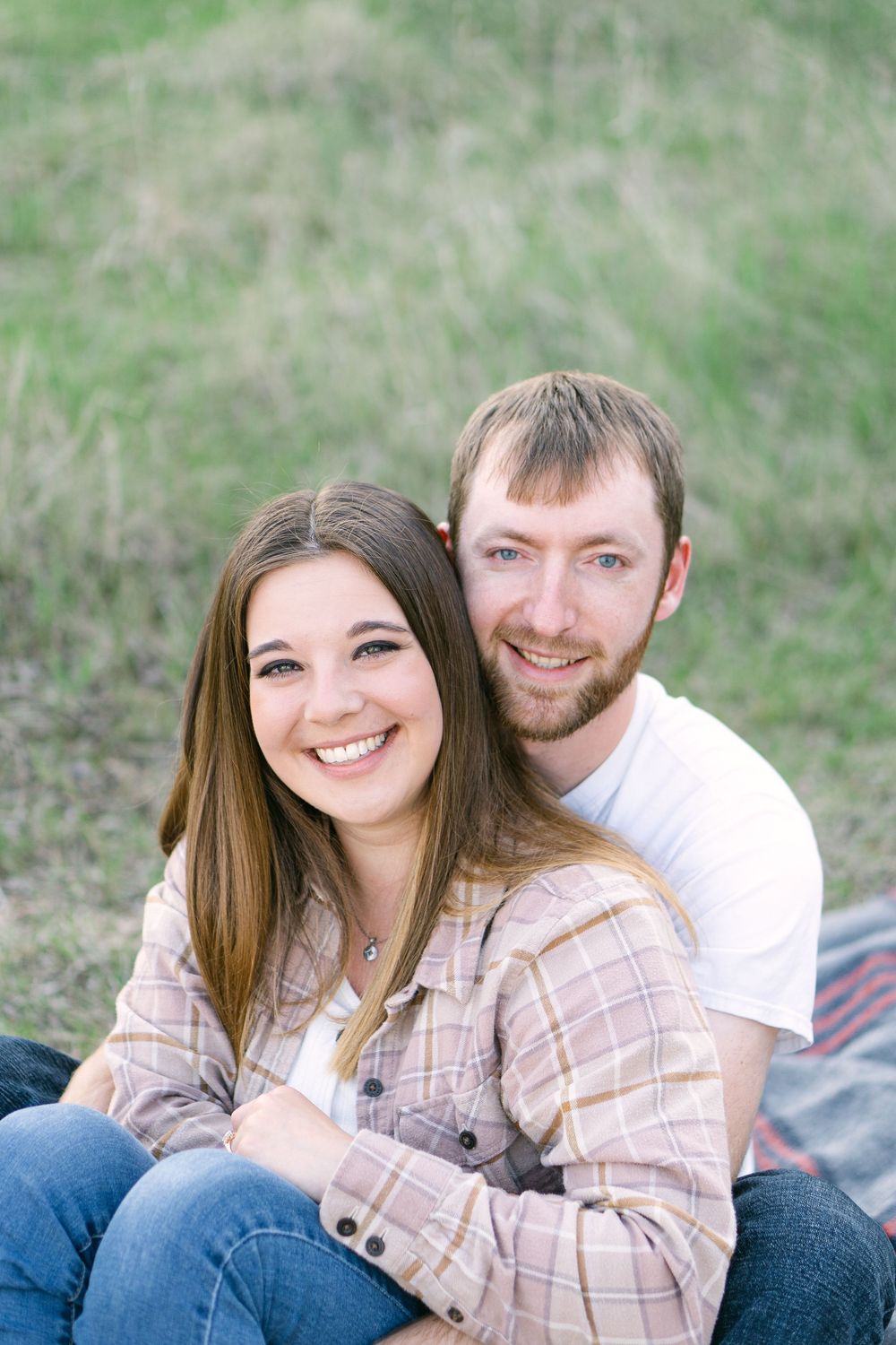 Romantic golden hour moment as couple cuddles on a blanket in a wide open field near Sauk Center