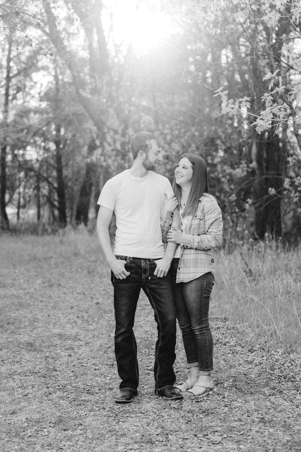 Engaged couple smiling at each other at sunset during a countryside engagement session outside St. Paul, Minnesota