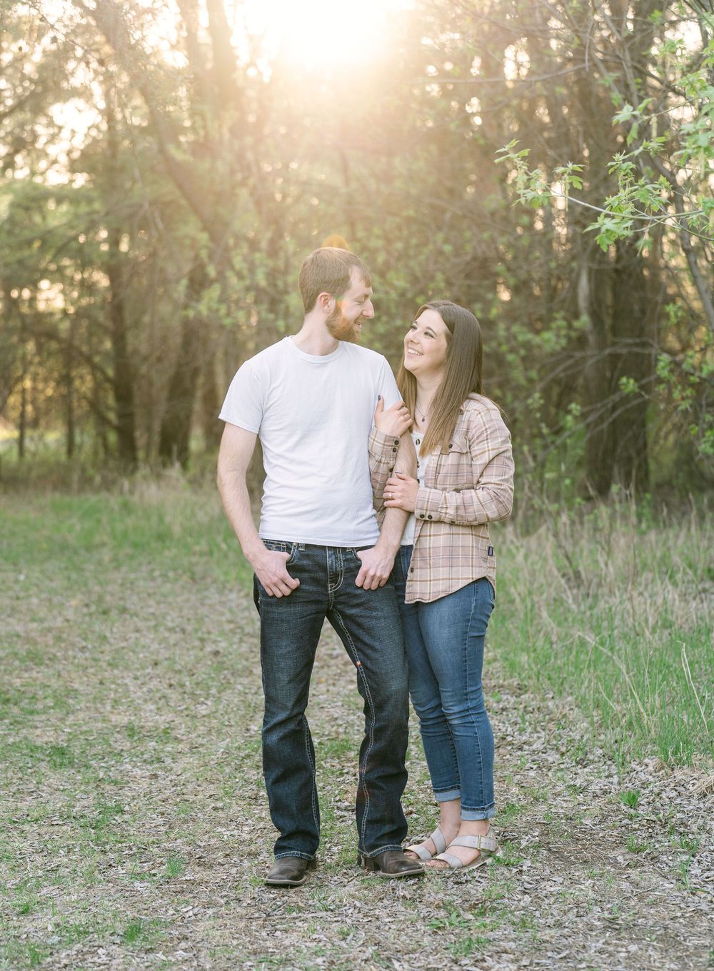 Engaged couple smiling at each other at sunset during a countryside engagement session in Melrose, Minnesota