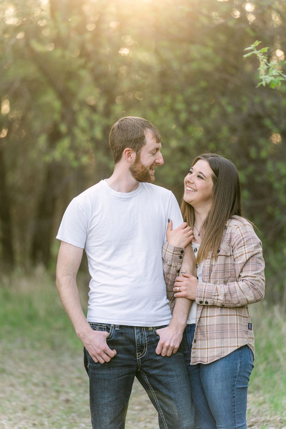 Couple smiling at each other and laughing at sunset during a countryside engagement session outside St. Paul, Minnesota