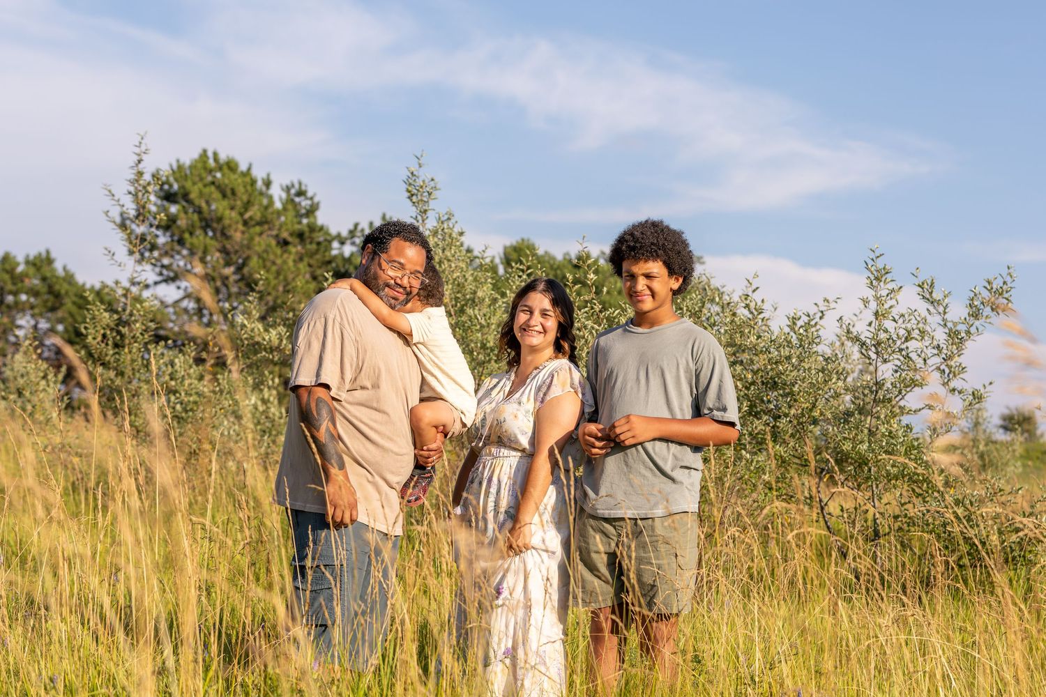 A group gathers in a golden prairie field under bright summer skies.