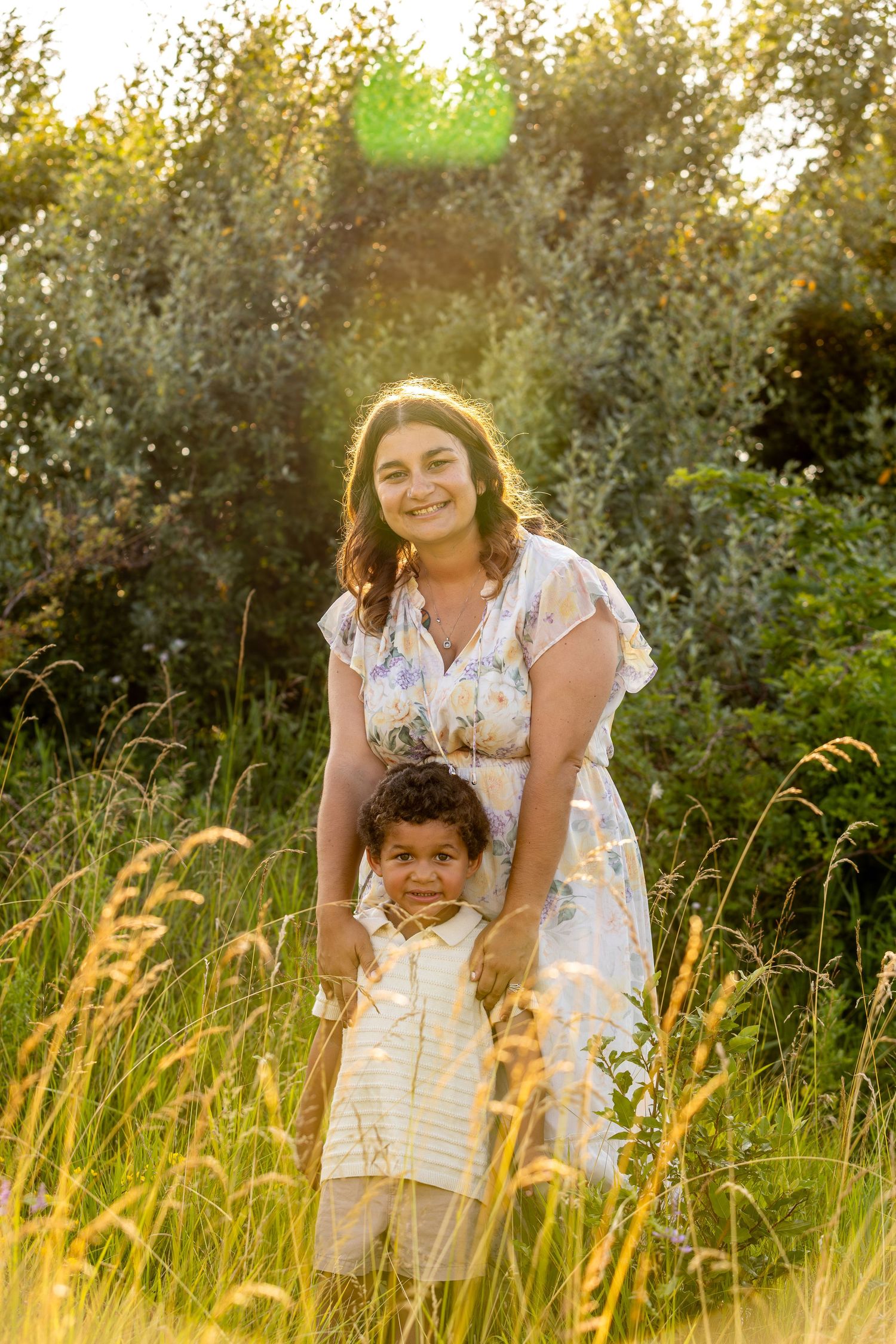 A touching outdoor portrait in golden sunlight amidst tall grass and greenery.
