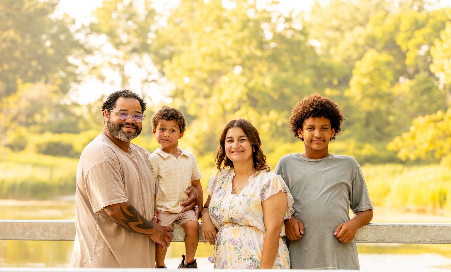 Family of four posing together in warm evening light outdoors.