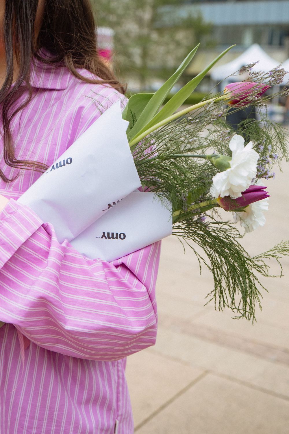 A pink and white striped linen dress shown from different angles with greenery and paper details.
