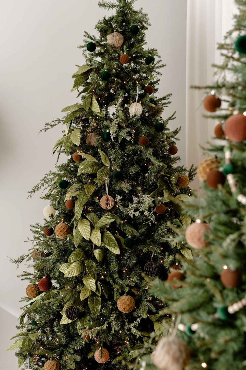 Elegant Christmas tree decorated with natural tones, featuring metallic ornaments and gold leaf accents.