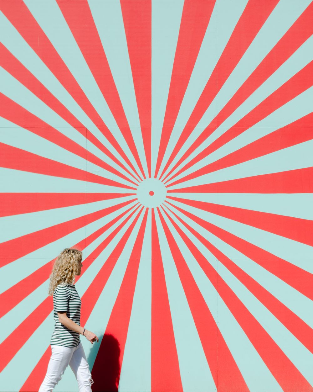 Dynamic red and turquoise radial sunburst pattern background with swirling rays emanating from center point.