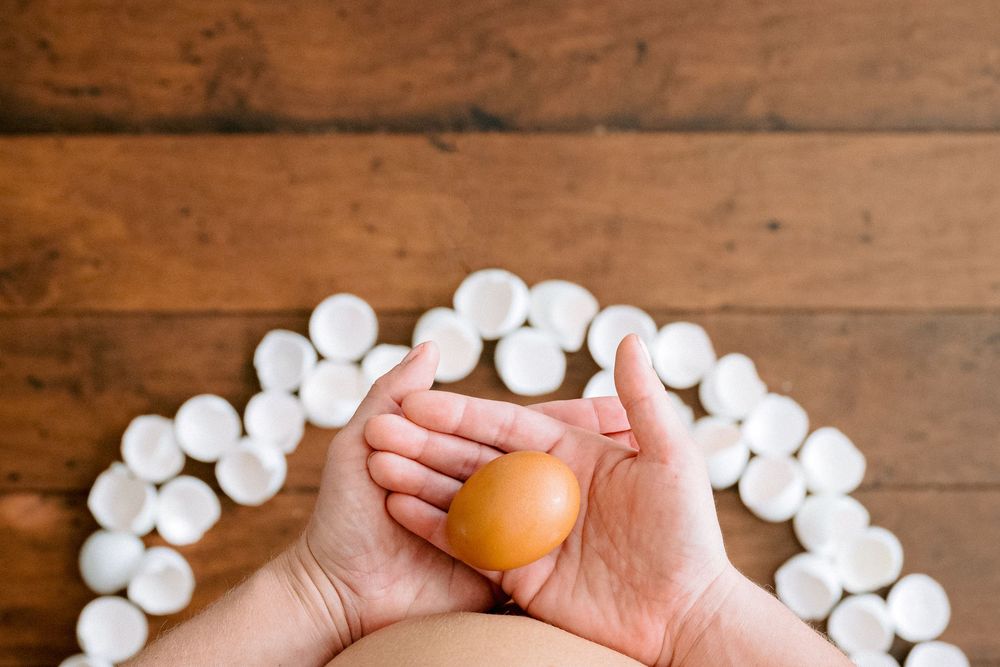 Hands holding Easter eggs with cotton ball decorations arranged in a garland craft project.