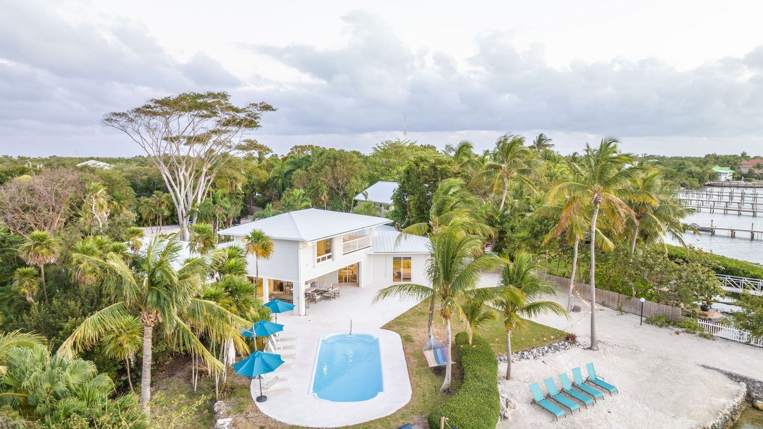 Aerial view of a tropical resort property with pools, palm trees, and lush landscaping.