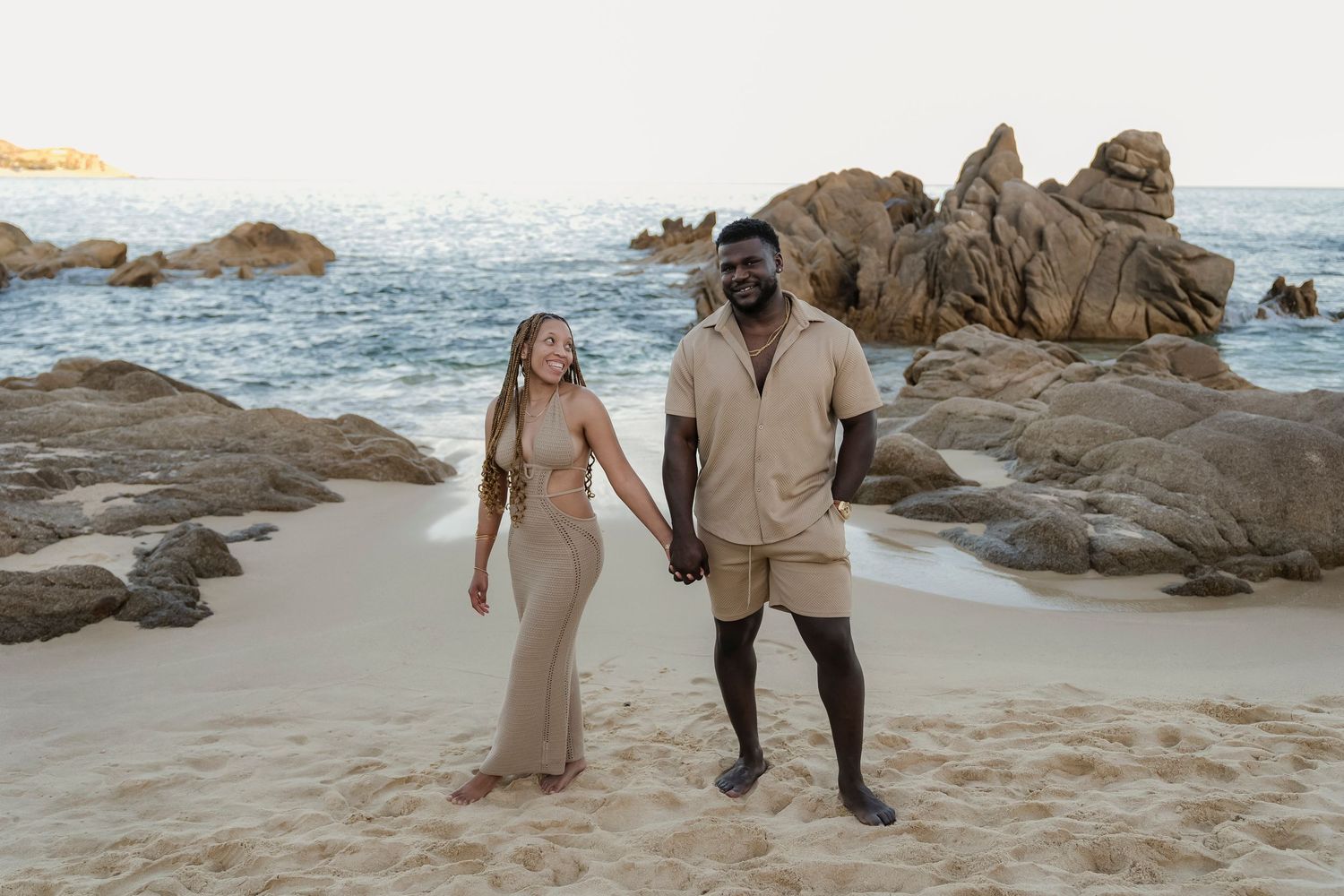 Bride and groom walking barefoot on Los Cabos beach at sunset
