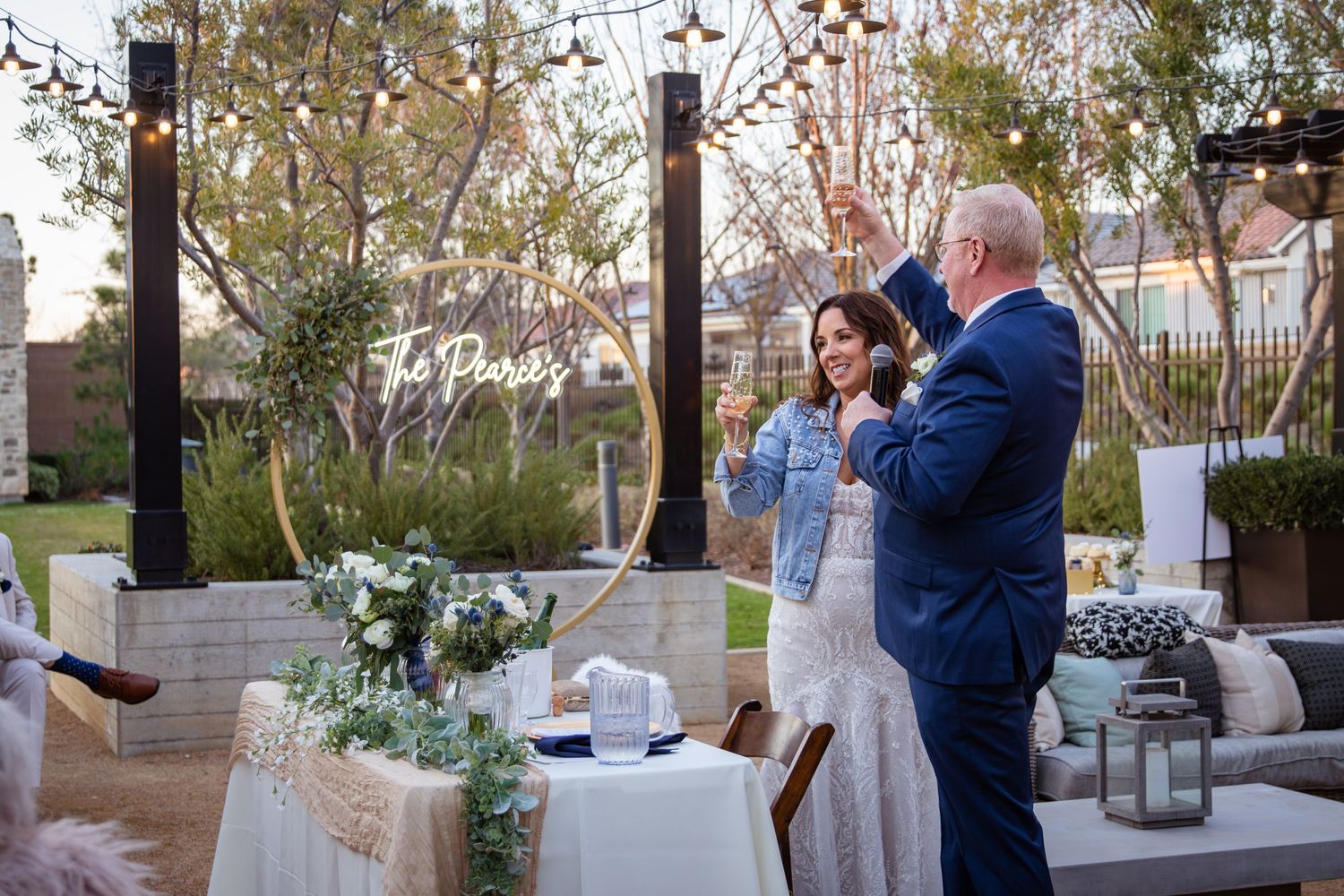 Outdoor wedding reception setup with string lights and elegant table decorations.