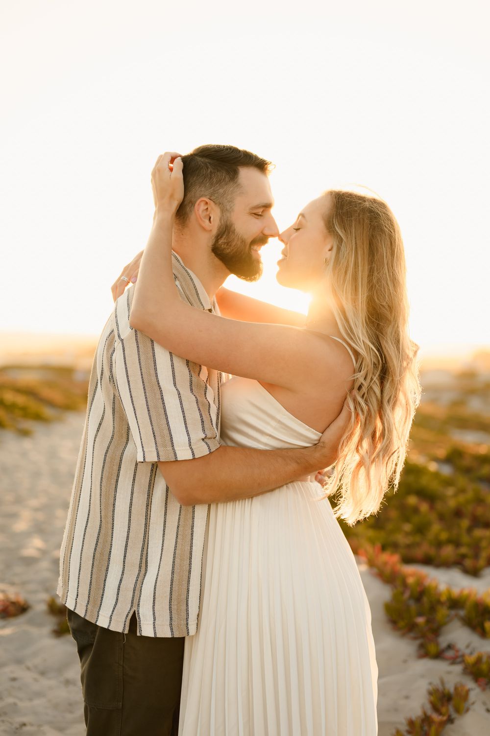 woman and husband go in for a kiss surrounded by golden sunlight during their maternity photoshoot by Ventura and Santa Barbara photographer