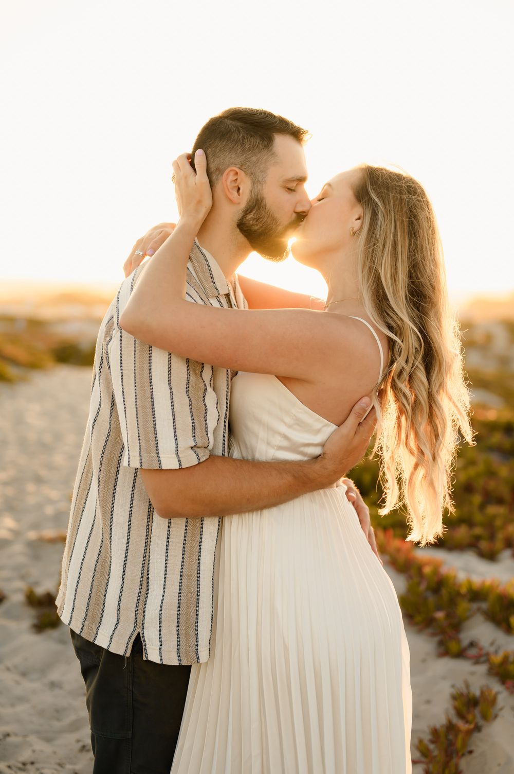 woman and husband go in for a kiss surrounded by golden sunlight during their maternity photoshoot by Ventura and Santa Barbara photographer