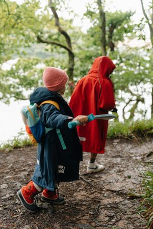 Children in colorful coats and hats exploring a wooded trail on an adventure.