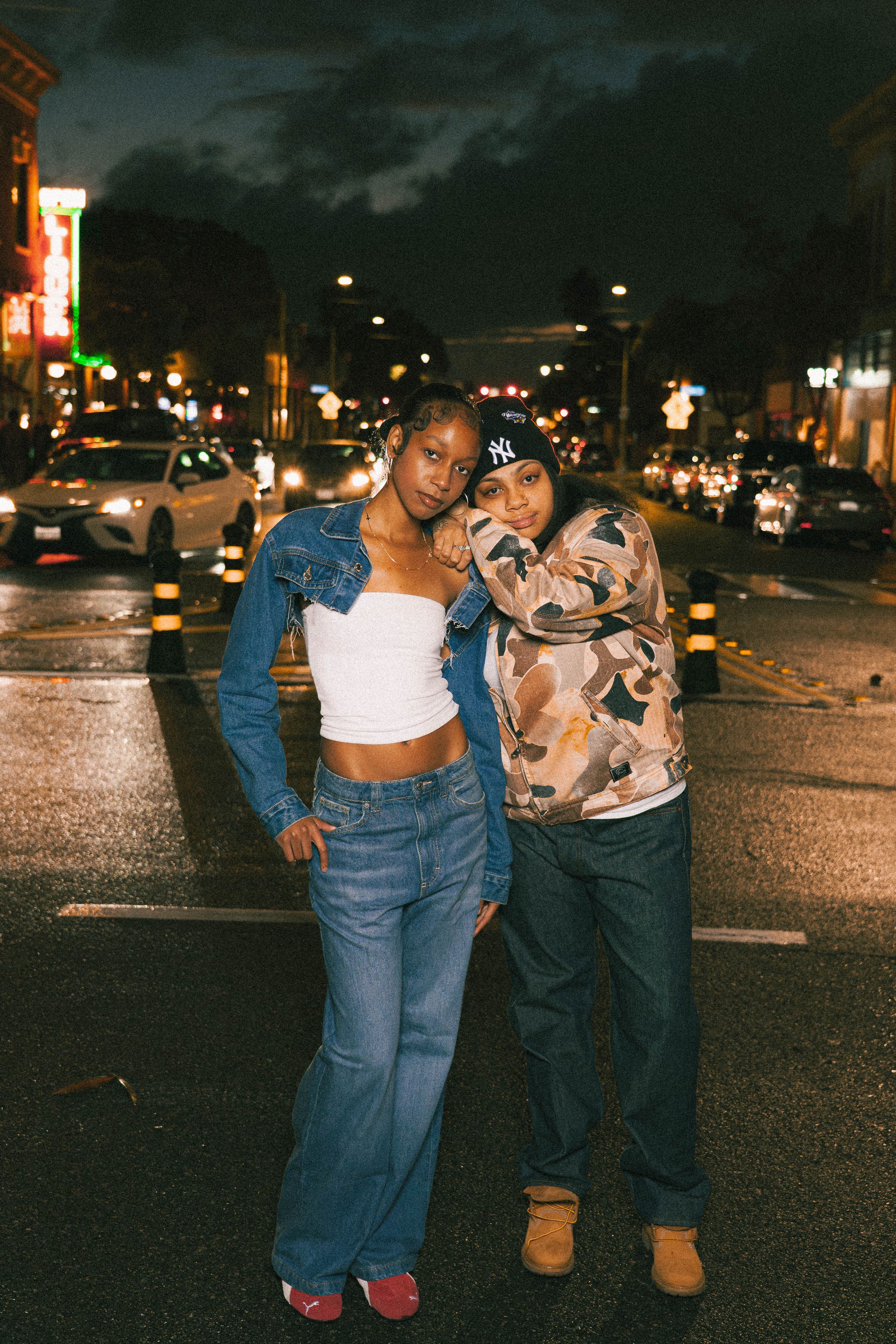 Three sequential photos of two friends dancing and posing playfully on a wet city street at night.