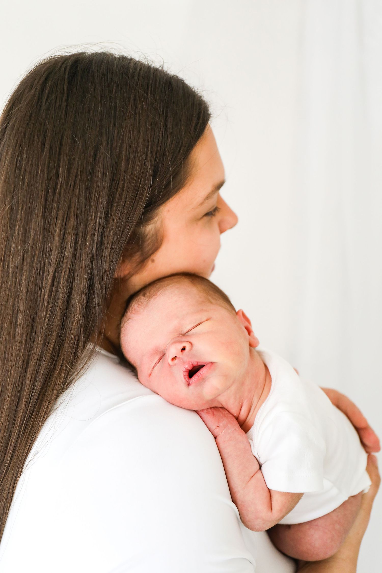 A sleeping newborn rests peacefully on mums shoulder in a heartwarming moment, during newborn shoot in Nottingham