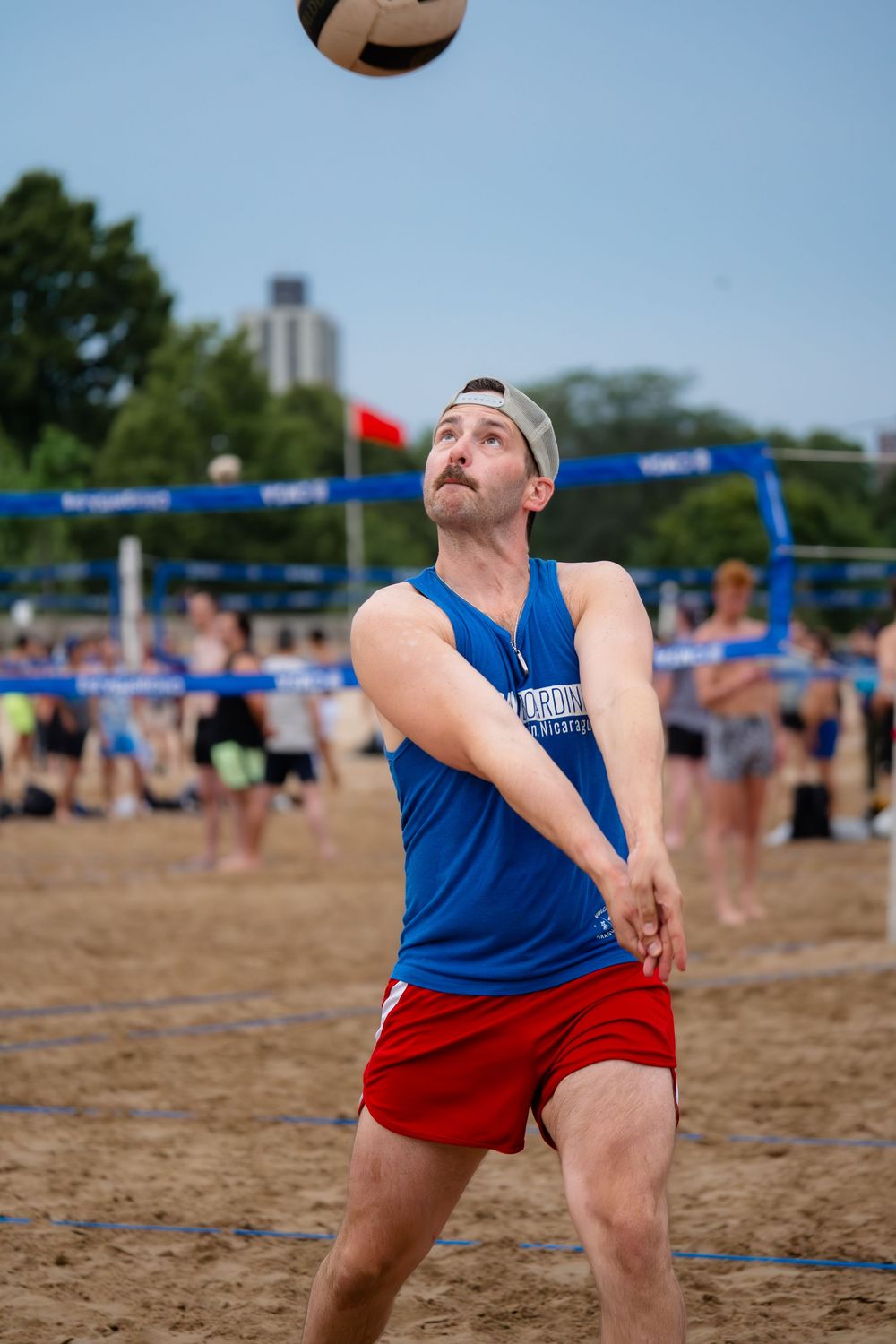 An athlete on the beach lines up a bump to return the ball over the volleyball net