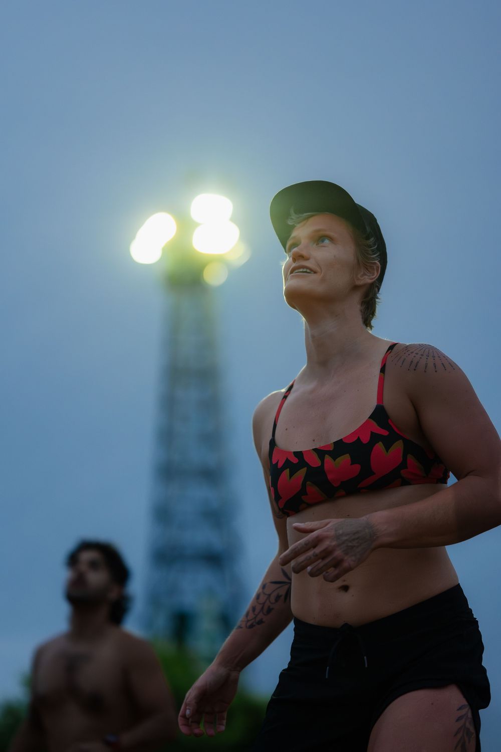 An athlete watches the play intently, backlit by a stadium light
