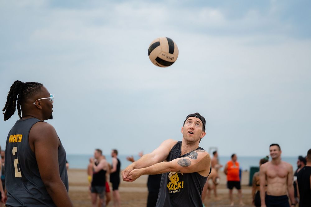 An athlete on the beach lines up a bump to return the ball over the volleyball net