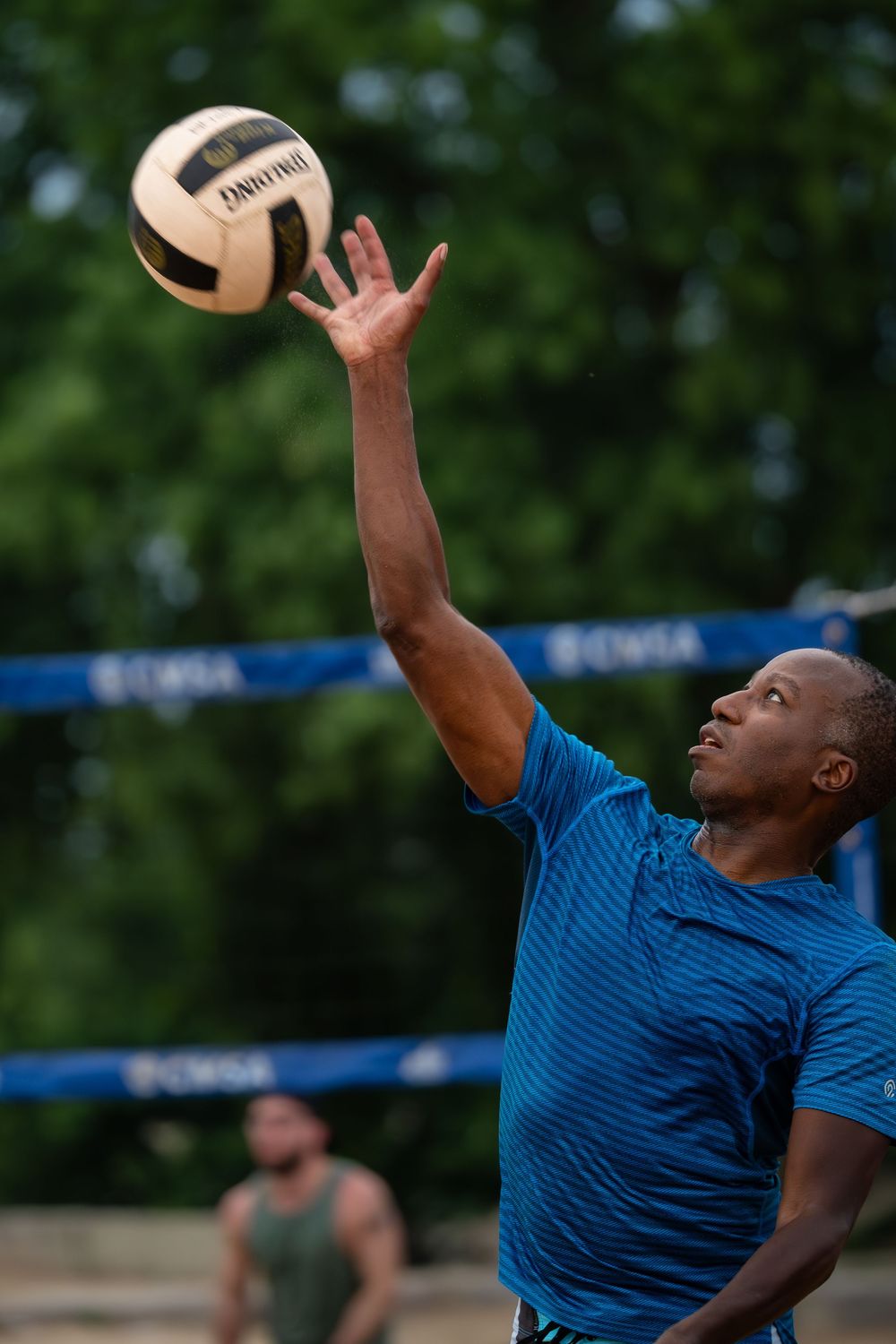 An athlete winds up to return the volleyball over the net to continue the point
