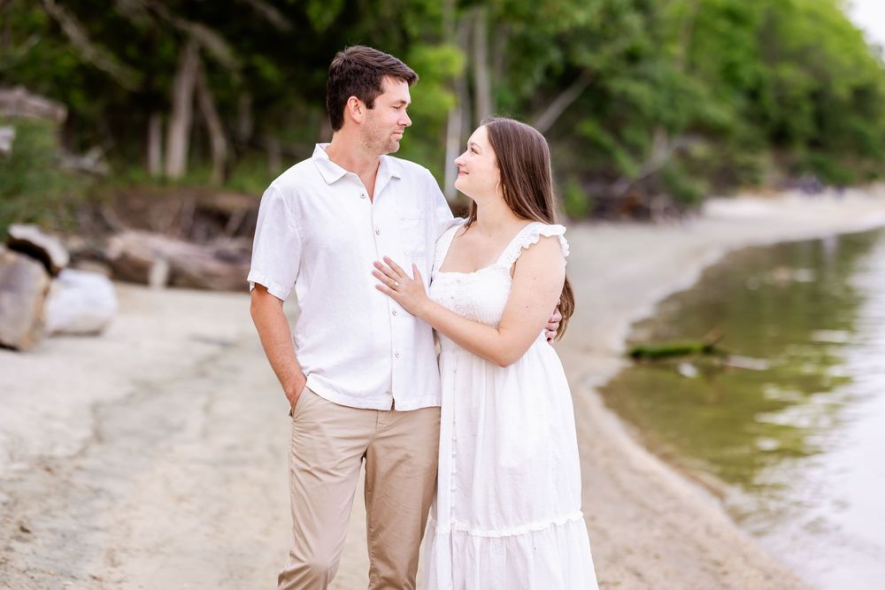 Couple in beachwear walking together and embracing on a tropical shoreline at sunset.