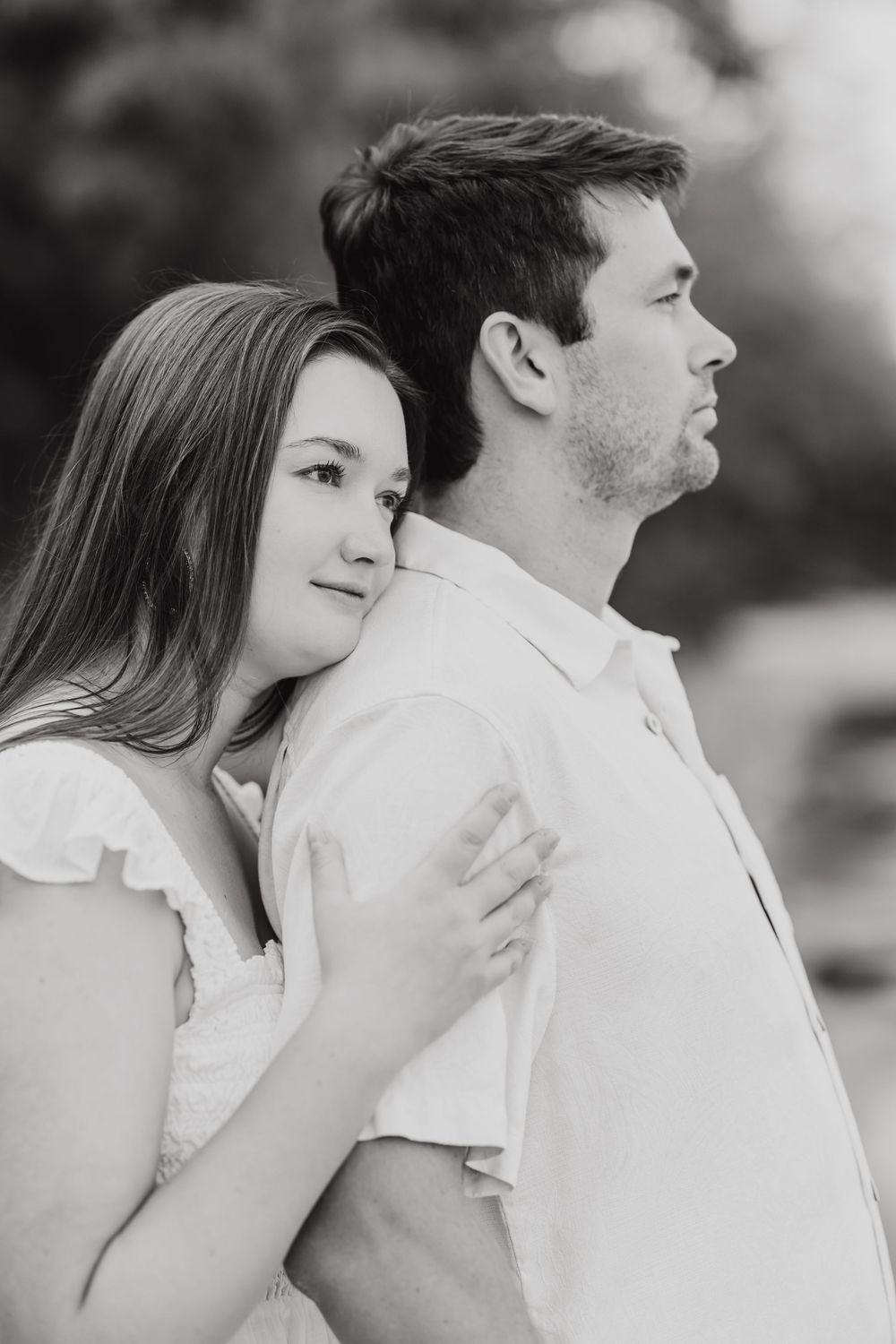 A romantic black and white portrait of a couple embracing while wearing white clothing, captured in a soft, dreamy style.