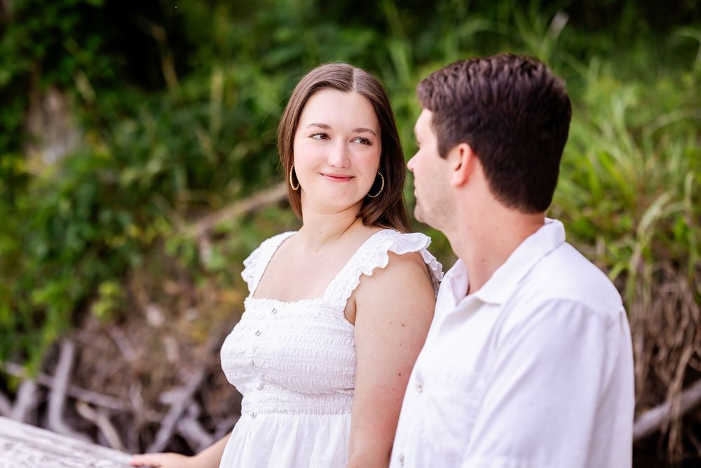 A happy couple in white attire sharing intimate moments together during an outdoor photo session.