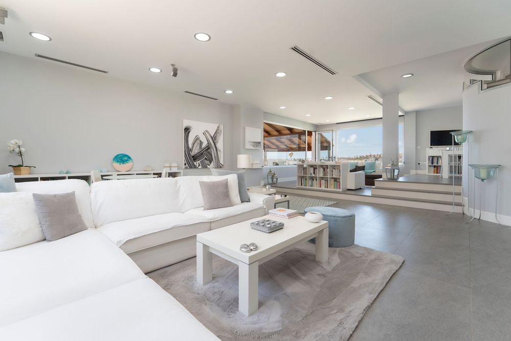 Modern white living space features minimalist decor, recessed lighting, and polished concrete floors in an open layout.