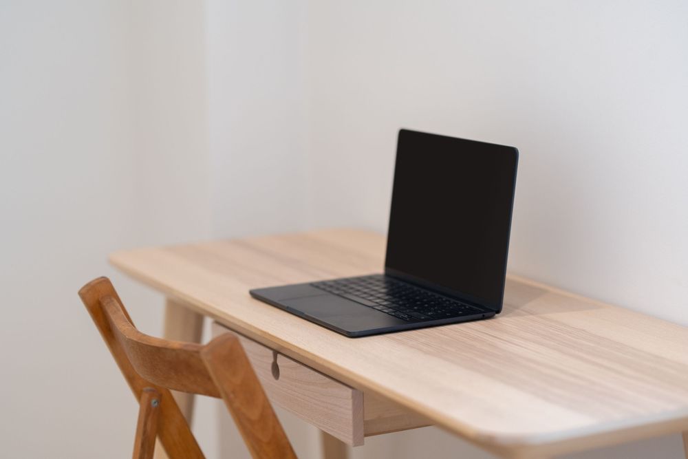 A wooden kitchen table with laptop and dining chairs shown from different angles in office setup.