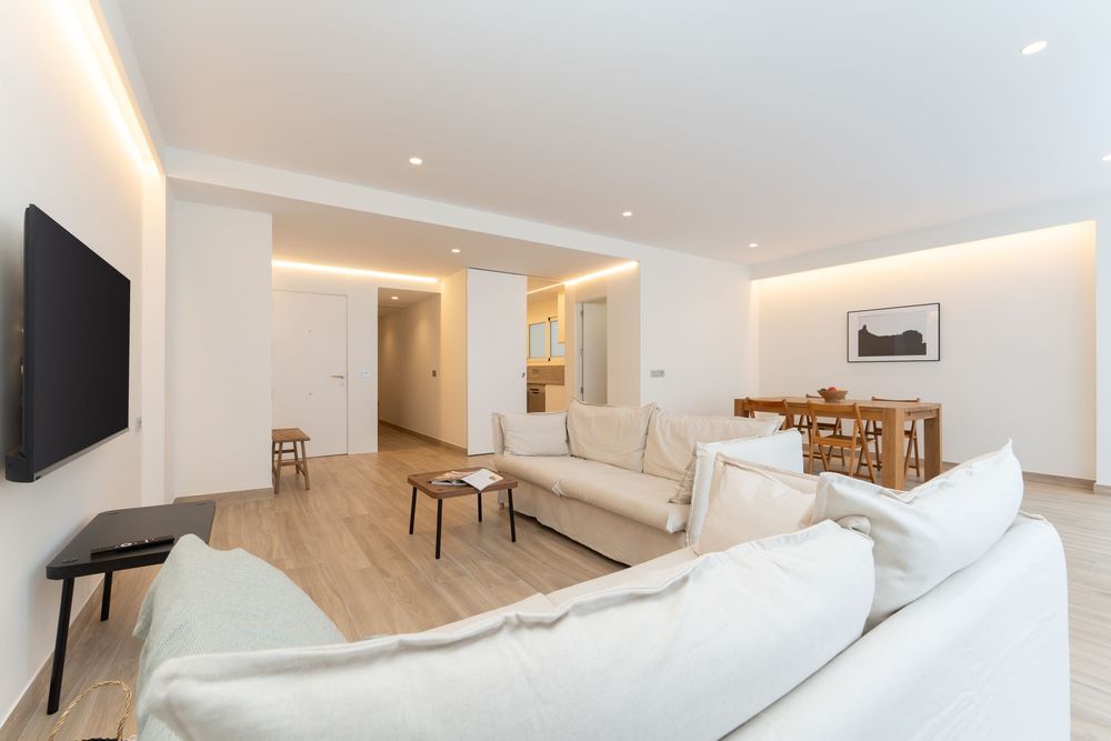 Modern open concept apartment interior with white walls, hardwood floors and minimalist decor throughout multiple rooms.