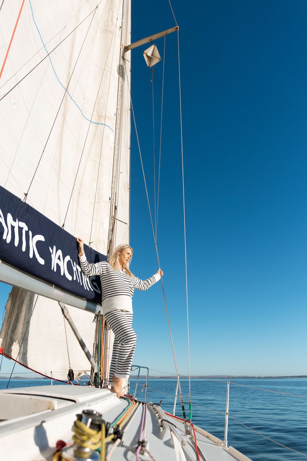 People enjoying a sunny day sailing on a yacht with blue waters and clear skies in the background.