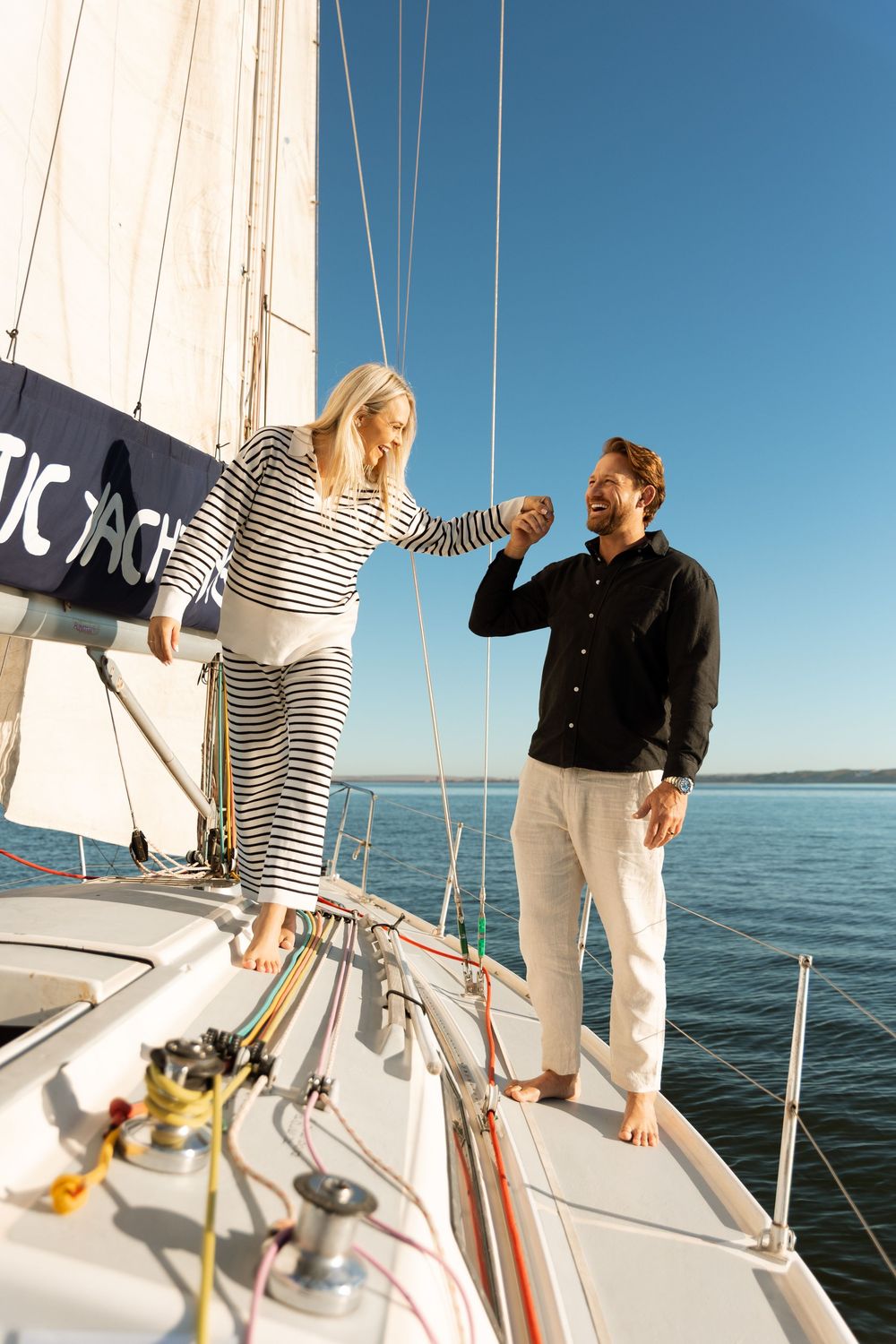 A group sailing on a boat deck with striped clothing against a bright blue ocean backdrop.