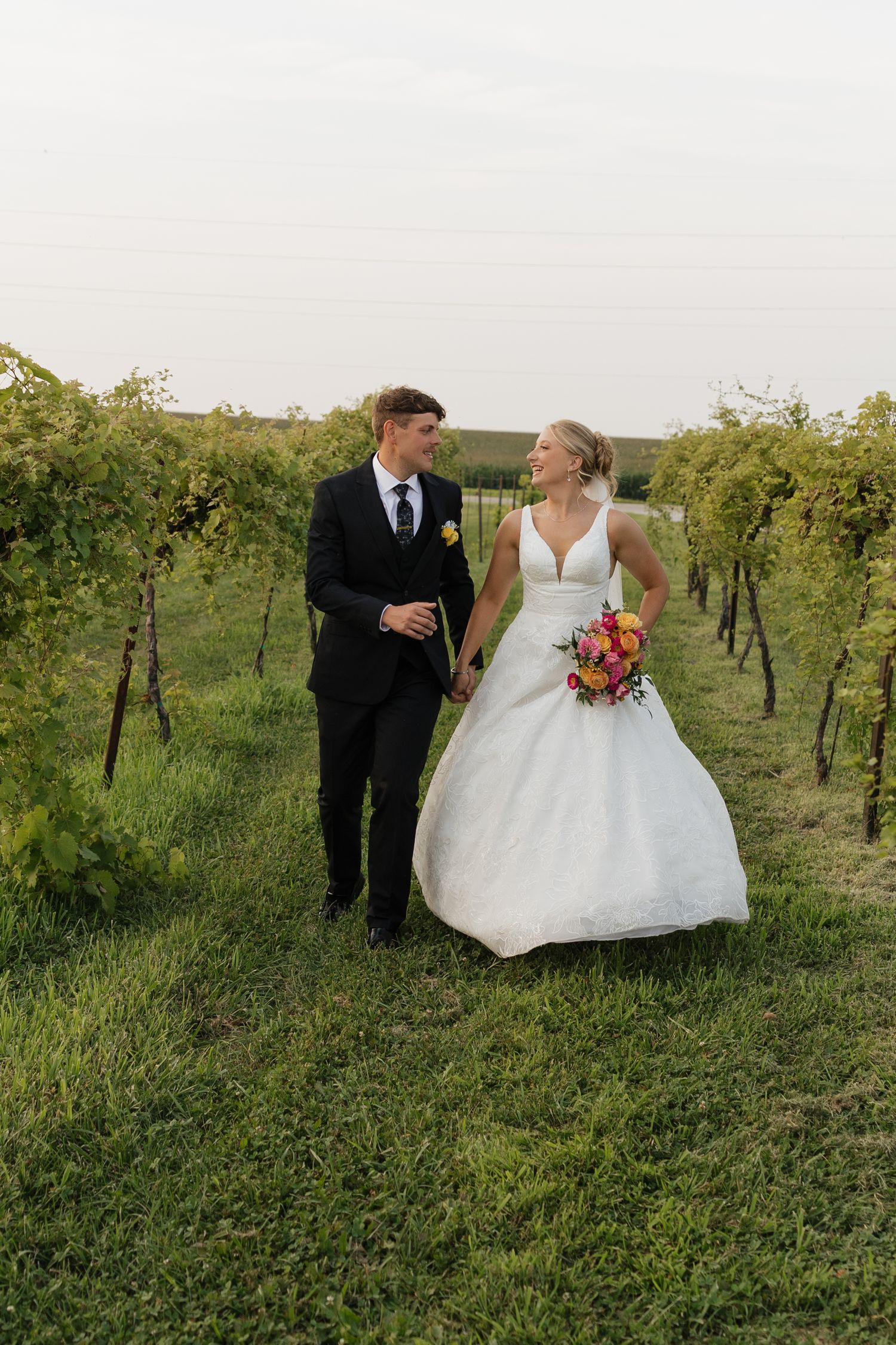 Newlywed couple embracing in white dress and navy suit during outdoor wedding photoshoot.