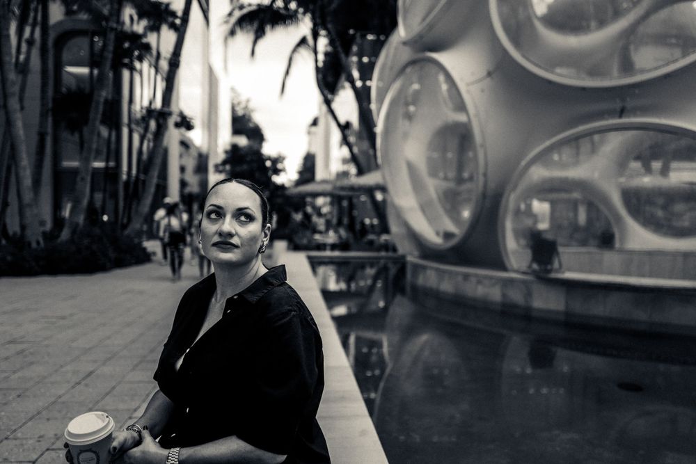 Urban street scene with palm trees and modern sculpture in black and white.