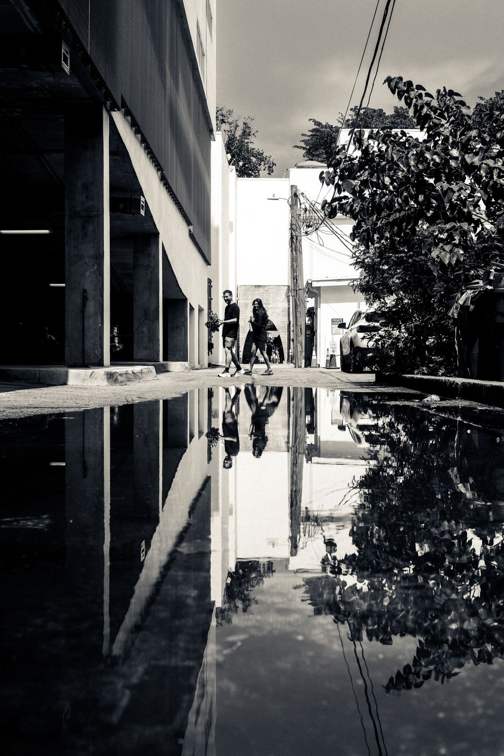 Reflective puddle creating mirror image of people walking between buildings.