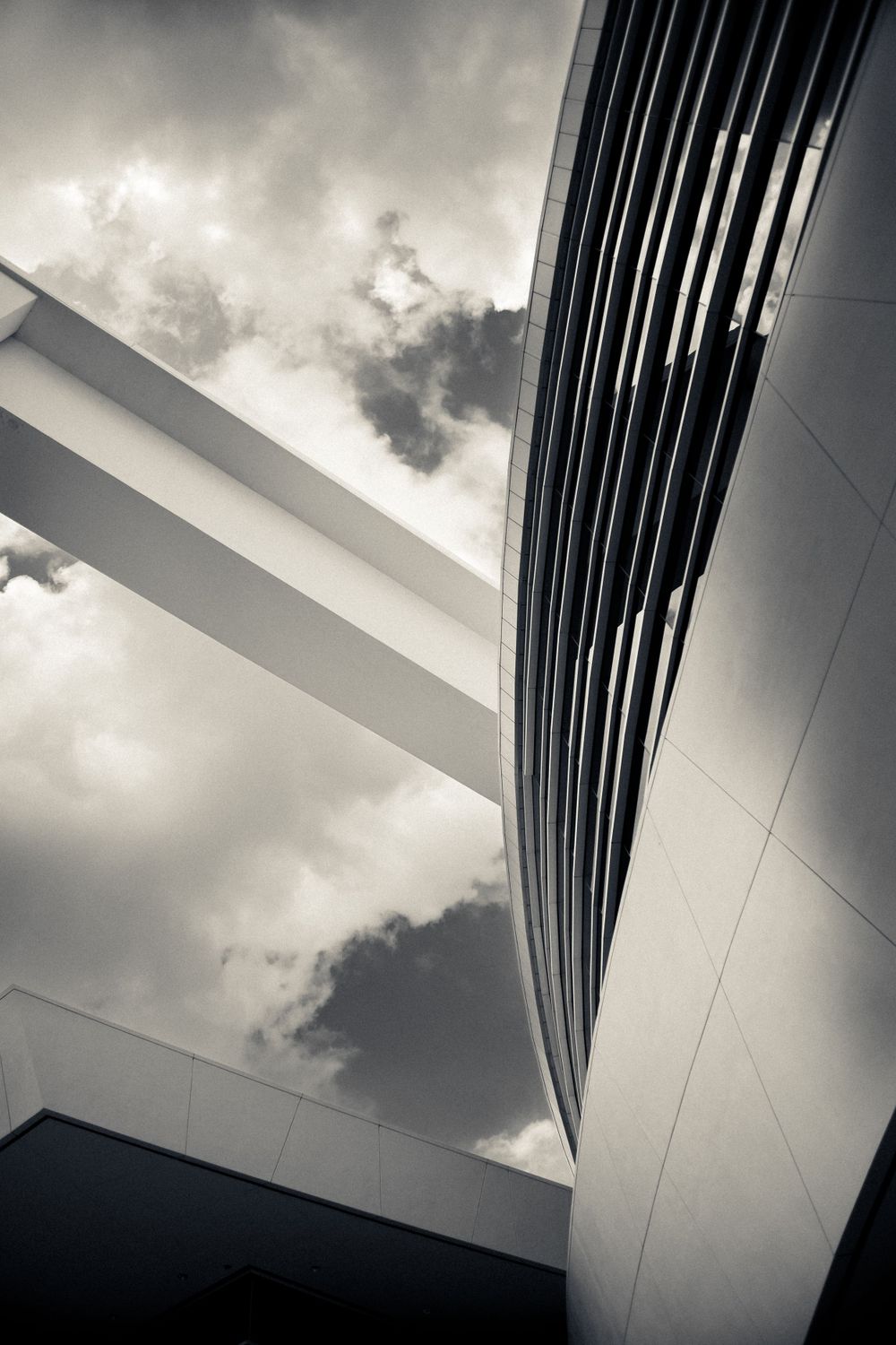 Modern architectural detail of white building facade against cloudy sky.