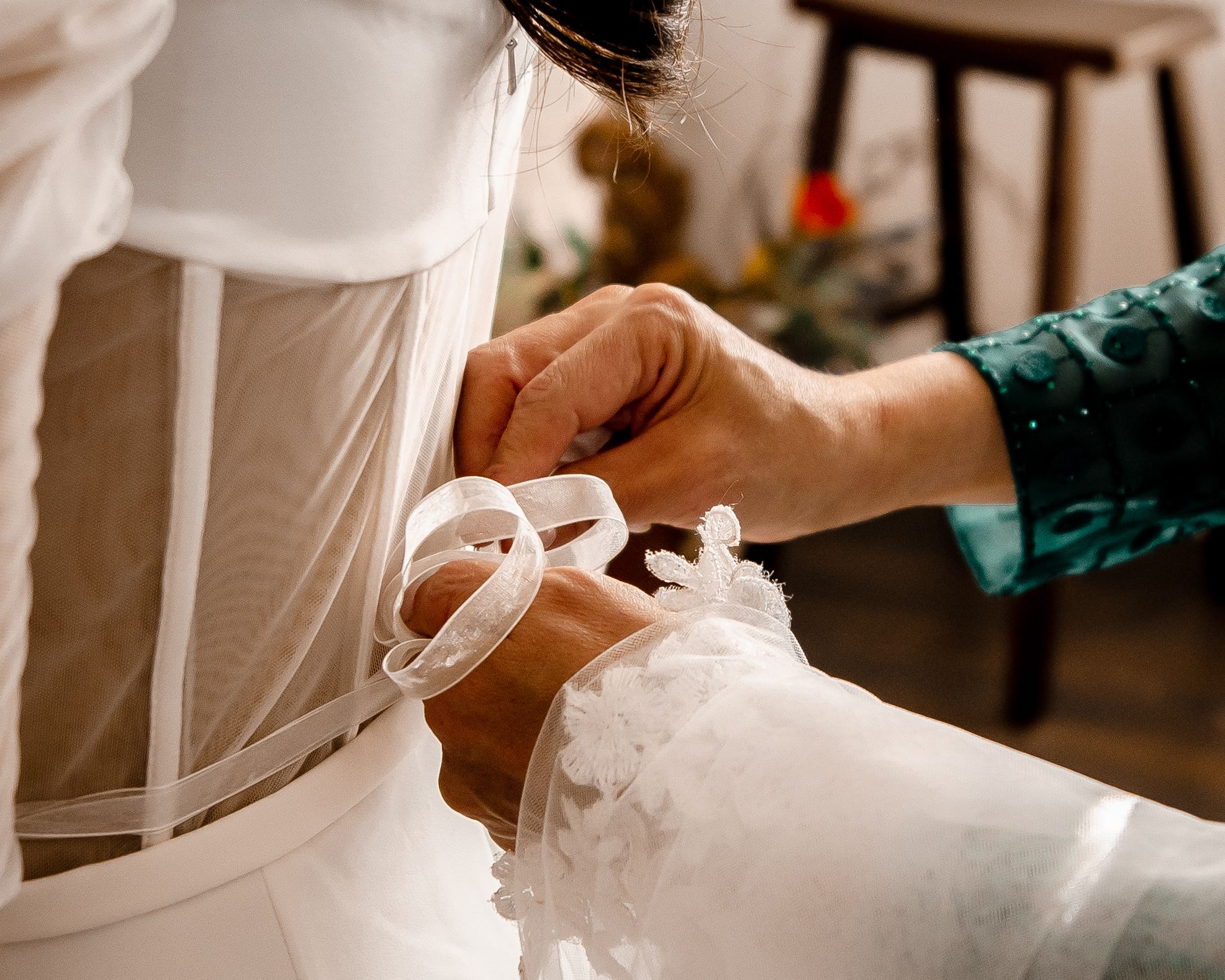 A close-up shot of hands adjusting the laces or ribbons on a white wedding dress.
