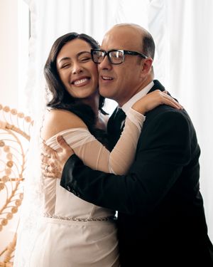 A couple shares a tender moment during their wedding photoshoot, embracing and smiling in a bright indoor setting.
