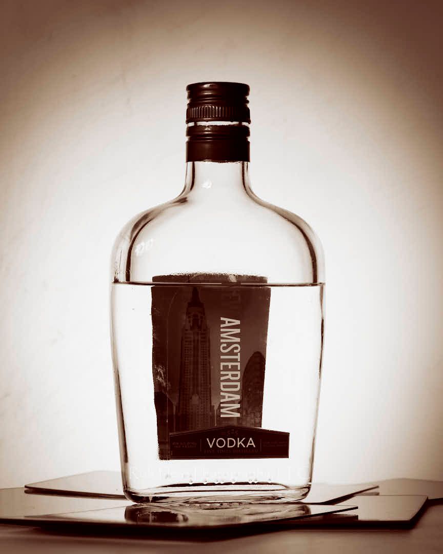 Sepia toned image of Amsterdam Vodka bottle with egg-shaped background light surround bottle.