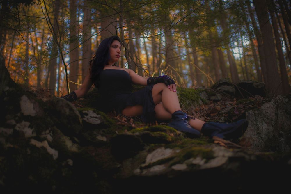 Atmospheric forest photoshoot with dramatic lighting and natural stone elements.