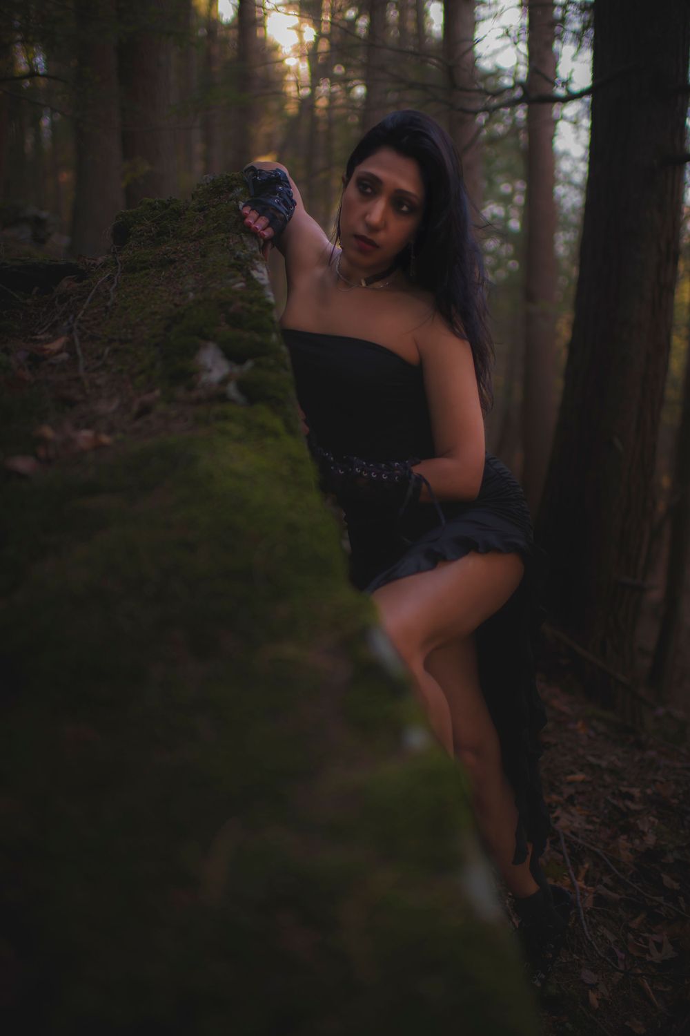 Dark forest photoshoot with a black dress and mossy woodland backdrop.