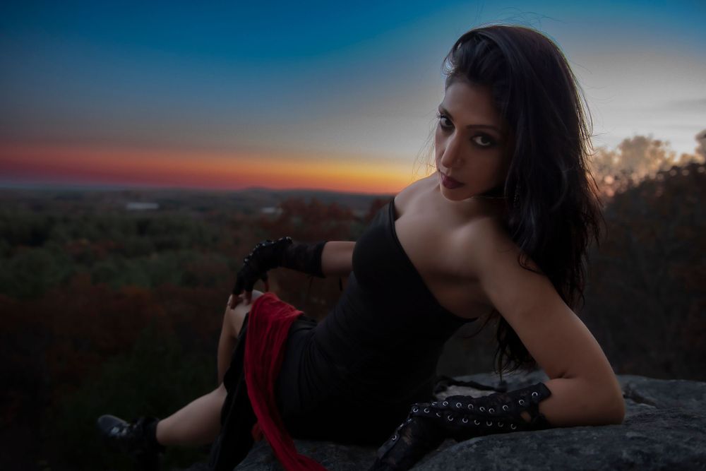 Moody sunset portrait on a mountain ledge with dramatic lighting and dark clothing.