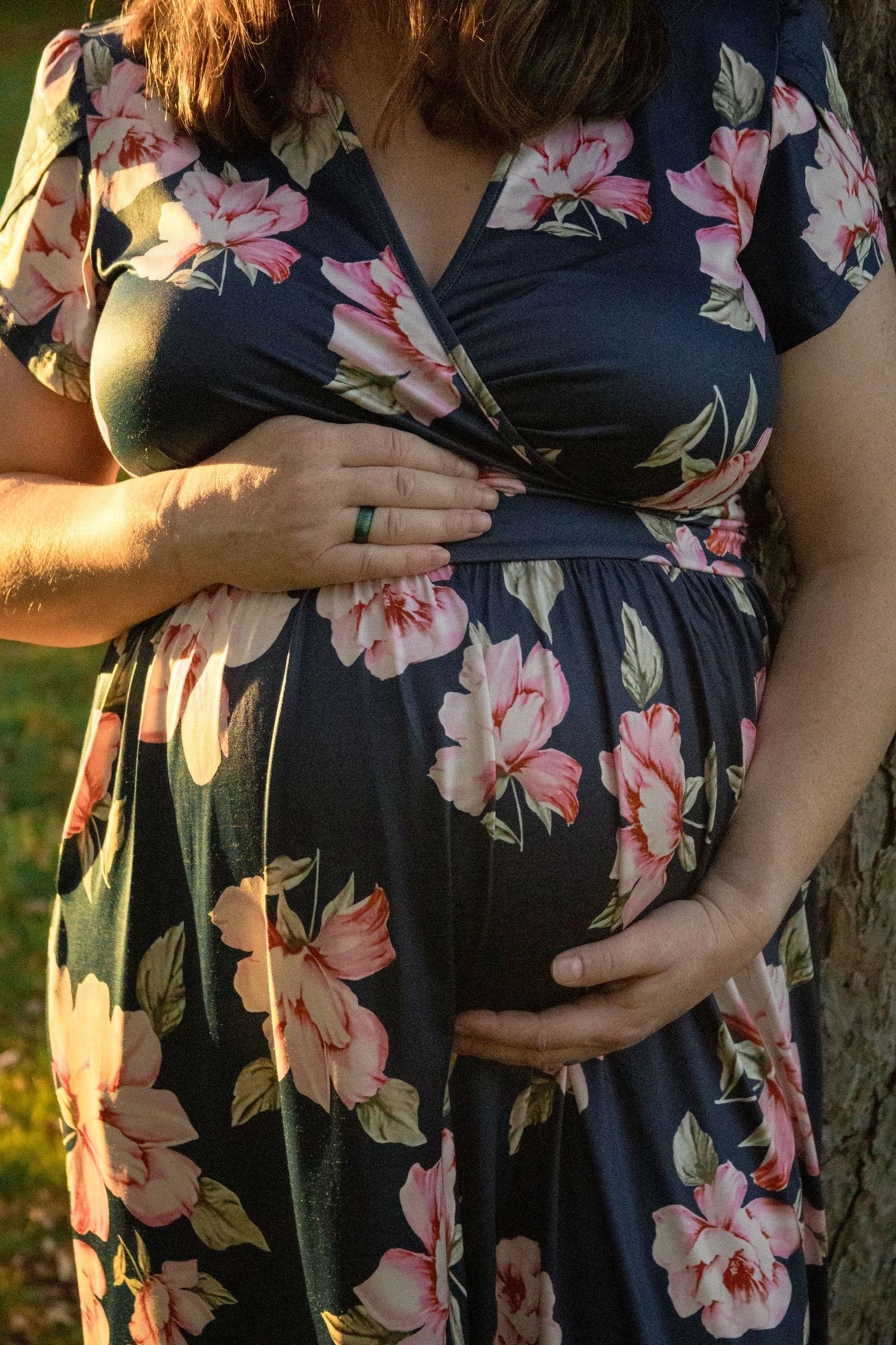 Maternity photos showing pregnant belly in floral dress during golden hour.