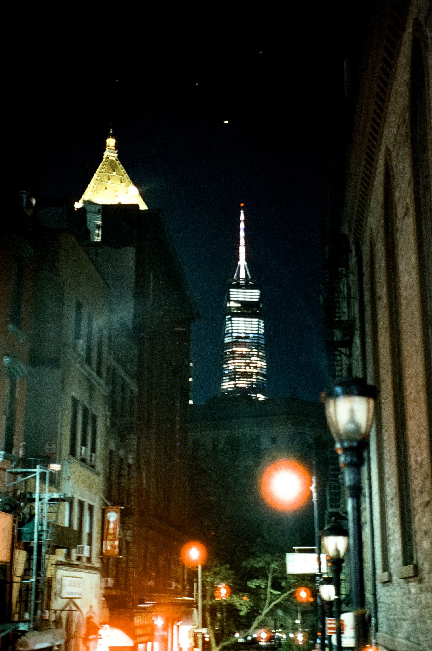 Empire State Building illuminated at night with street lamps glowing in the foreground.