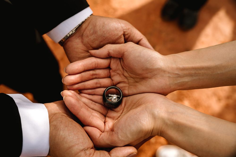 Close-up of hands holding a wedding ring during an outdoor Sedona ceremony.