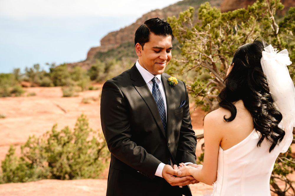 A couple exchanges vows during their outdoor wedding with Sedona desert mountains in the background.